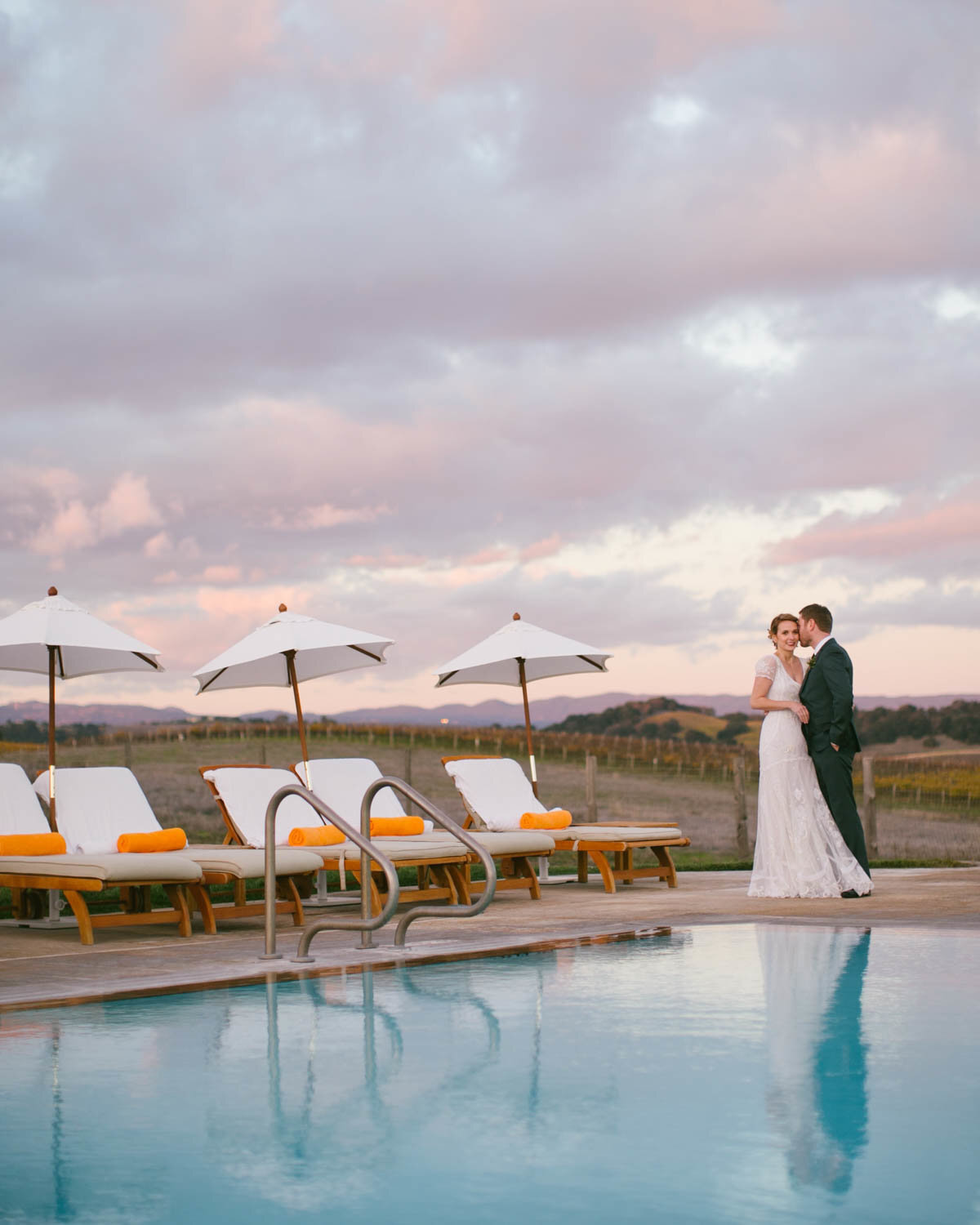 Shot from across a pool of Bride + Groom