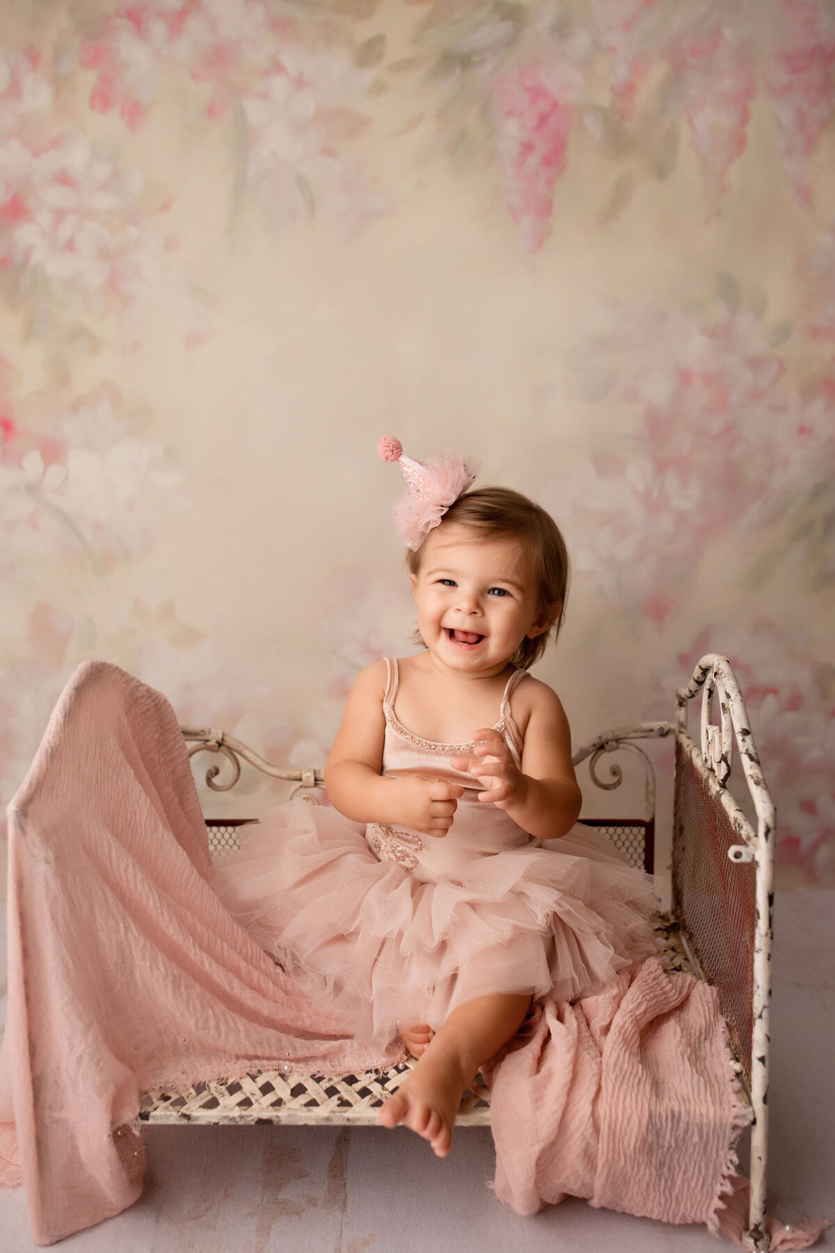 baby girl on a pink tutu sitting in a metal bed