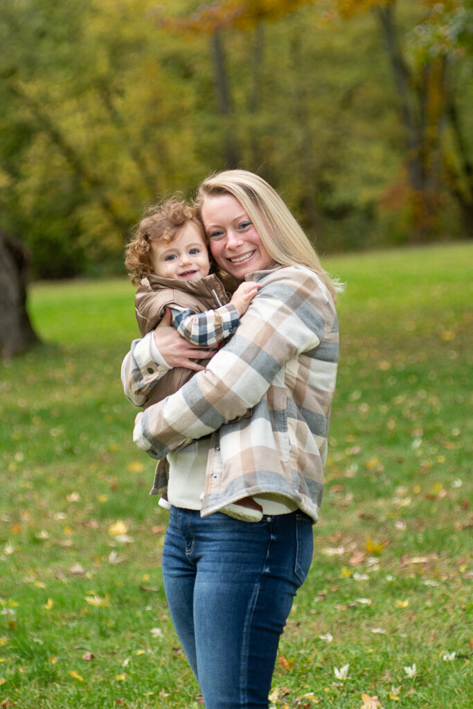 Mom snuggles happy toddler at park