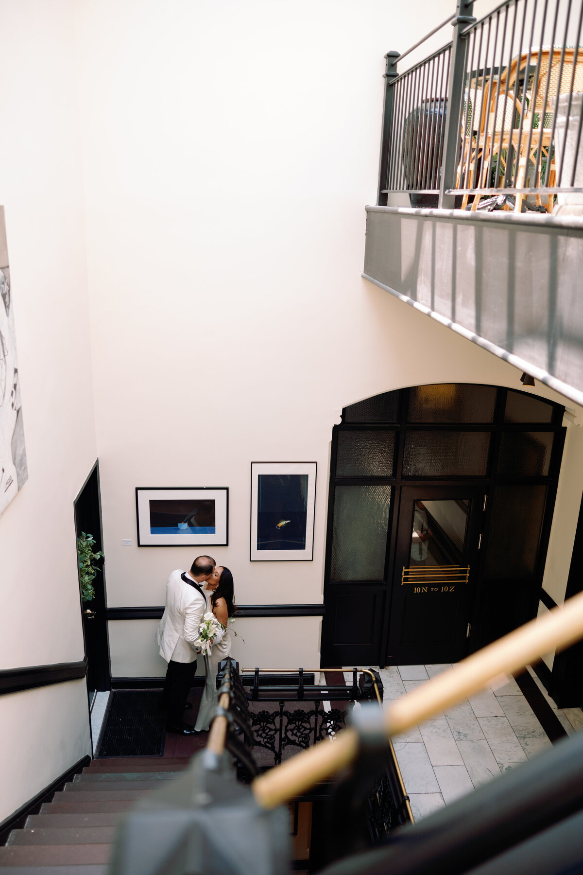 Candid black-and-white moment of the bride and groom mingling with guests inside a stylish modern venue.