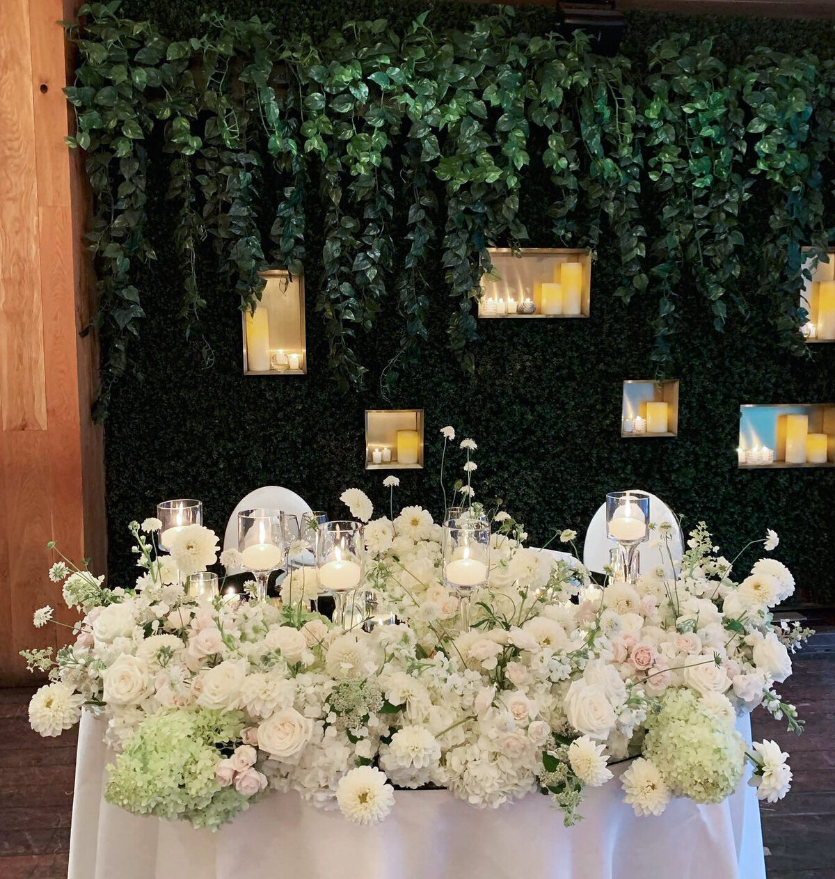 A sweetheart table at a Restaurant Beatrice wedding is lined with lush white flowers.