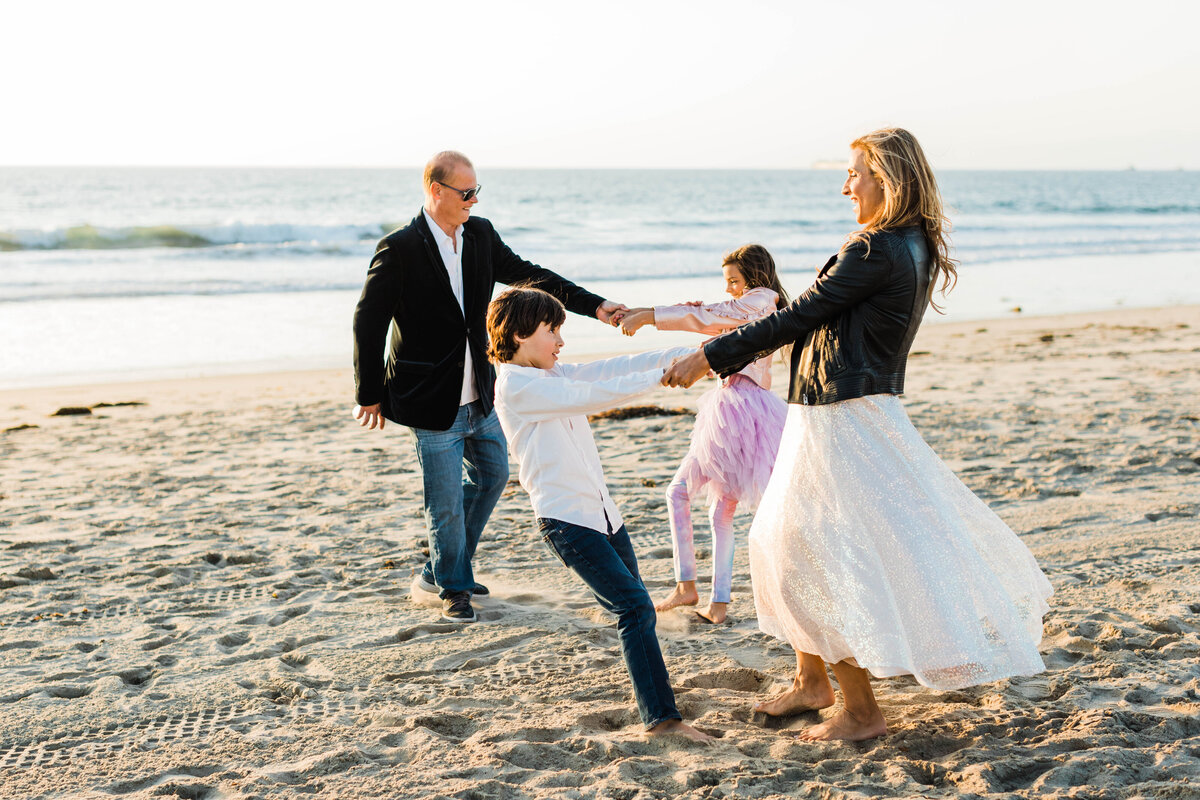 family-playing-on-manhattan-beach-at-sunset