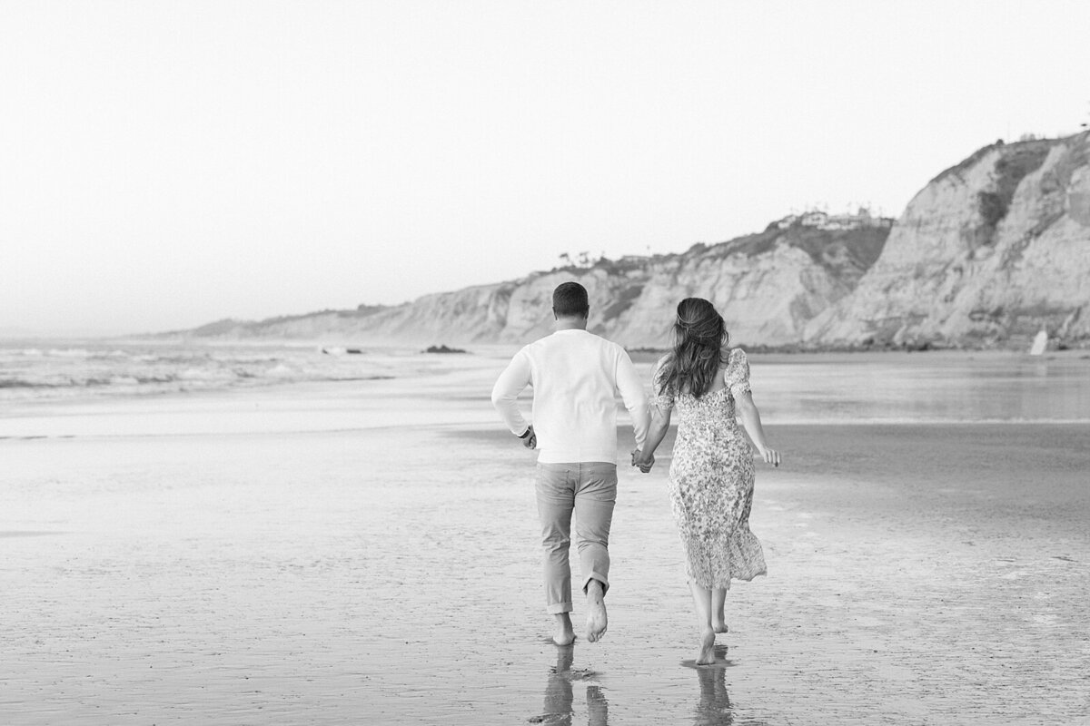 Couple running on the beaches of La Jolla by Lisa Riley Photography