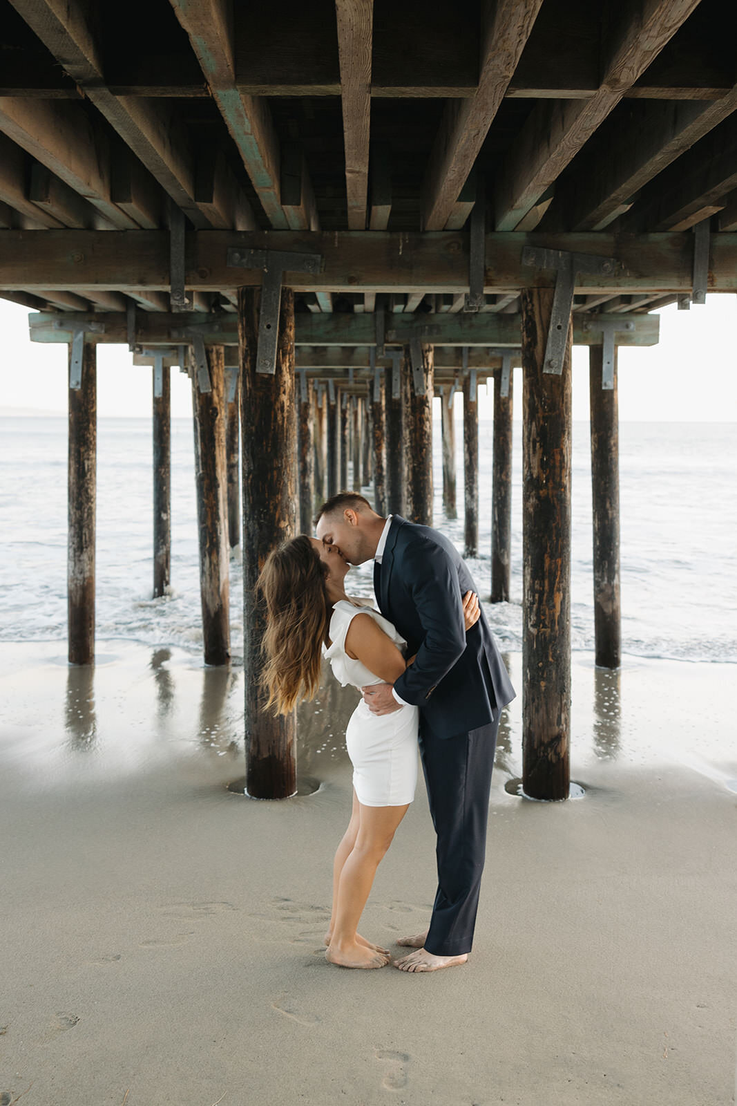 Couple kissing under a pier