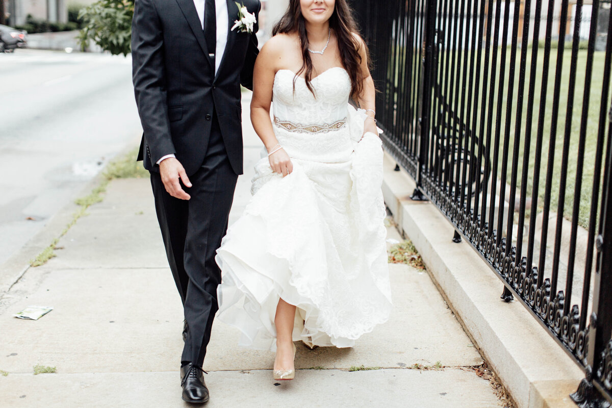Bride and groom walking down sidewalk after wedding. 