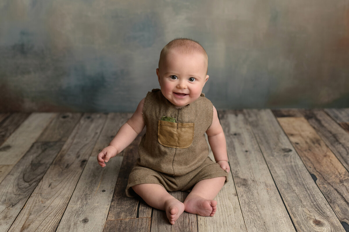 six month old baby sitting up and smiling during photoshoot