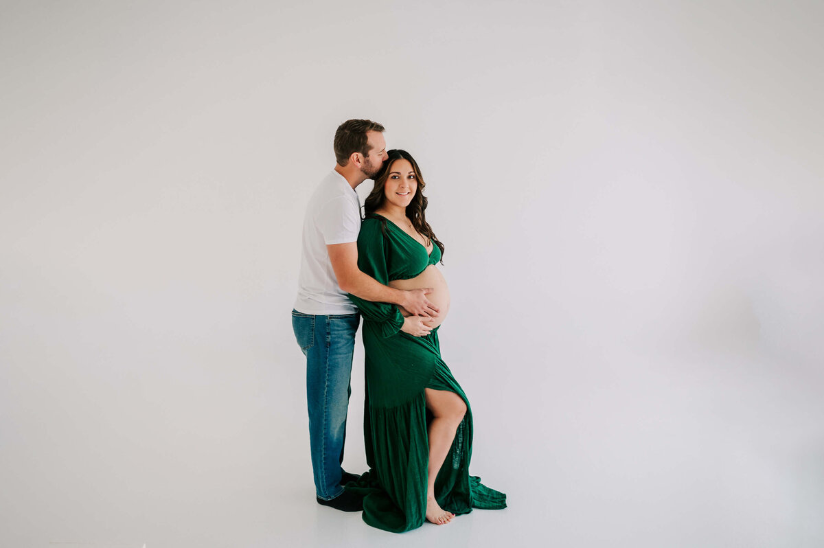maternity photo in Springfield Mo of husband kissing pregnant mom head holding baby bump