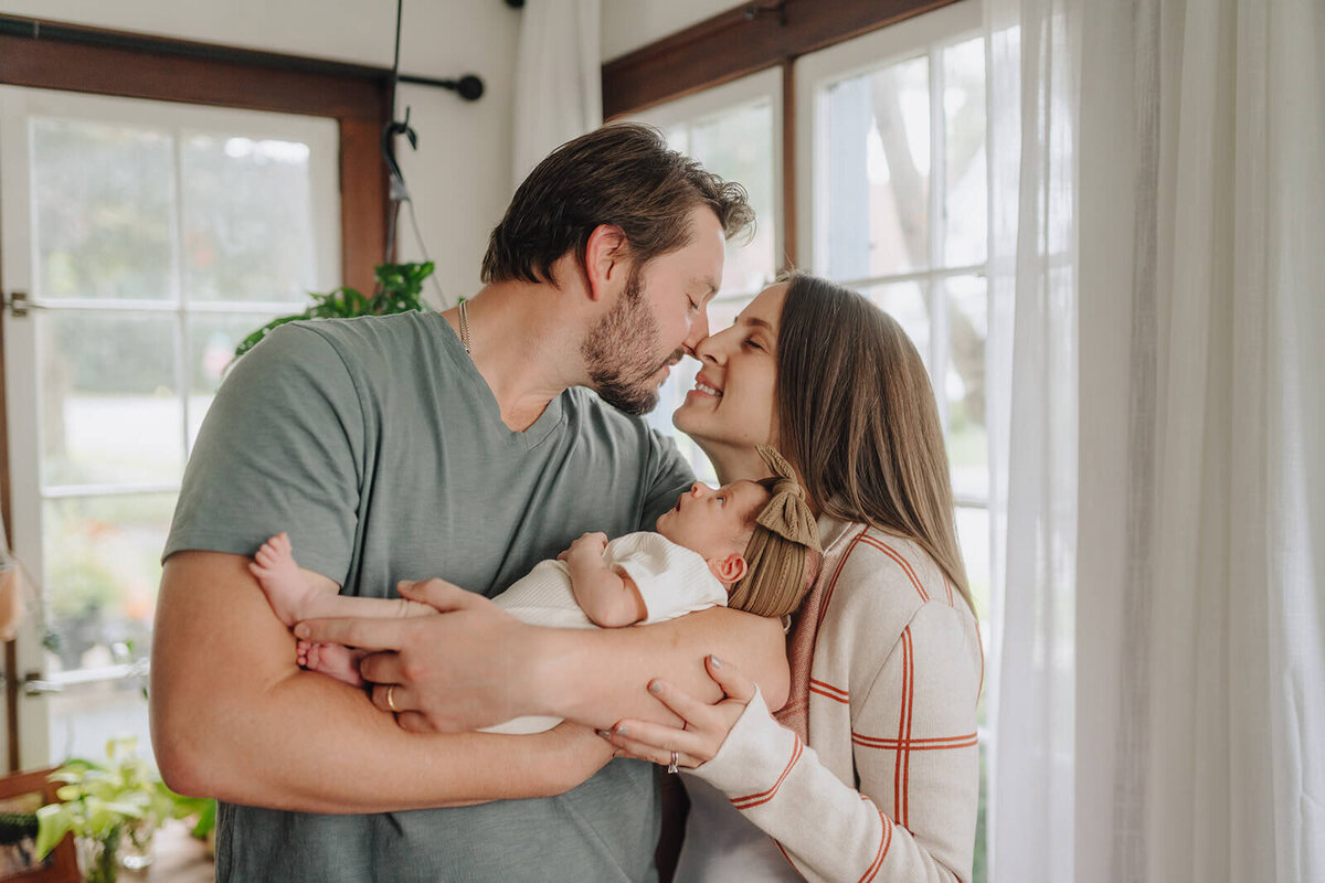 Couple touching noses holding a newborn baby at newborn photoshoot at Finger Lakes, NY