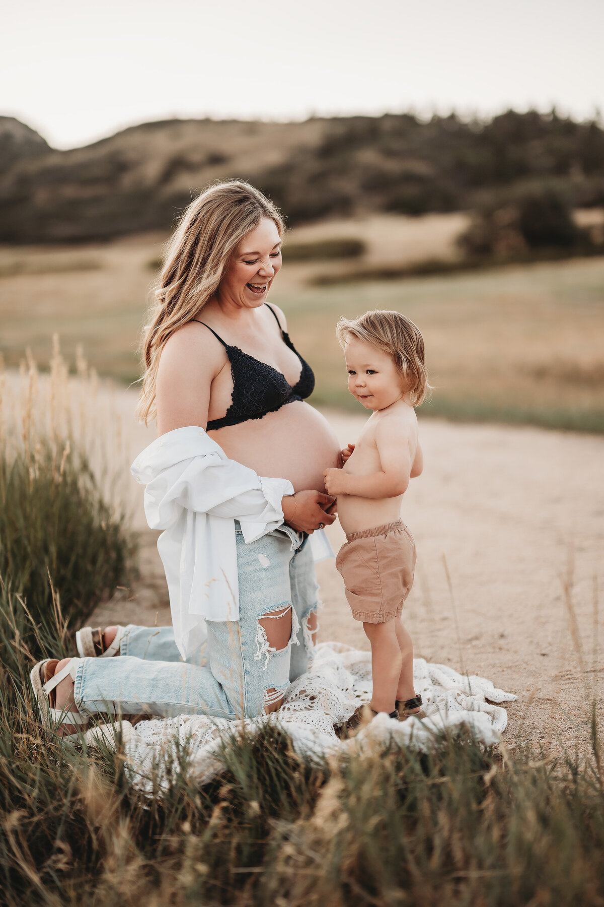 boy holding his bare belly up to mom's bare pregnant belly