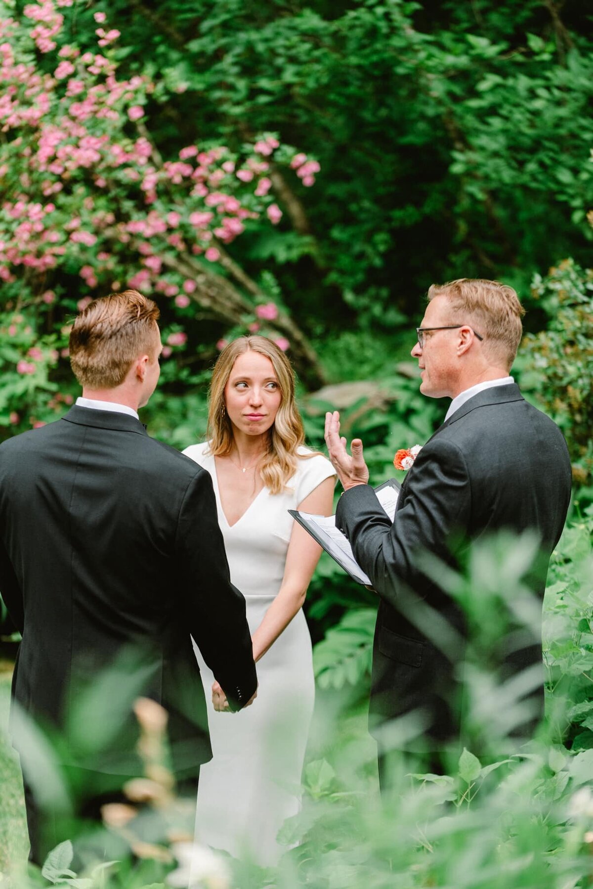 Bride and groom look at officiant in Secret Garden at Clifton Inn wedding