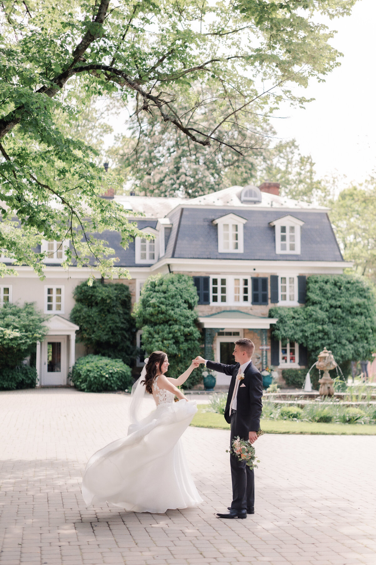 Editorial candid of bride and groom twirling in front of their french inspired wedding venue