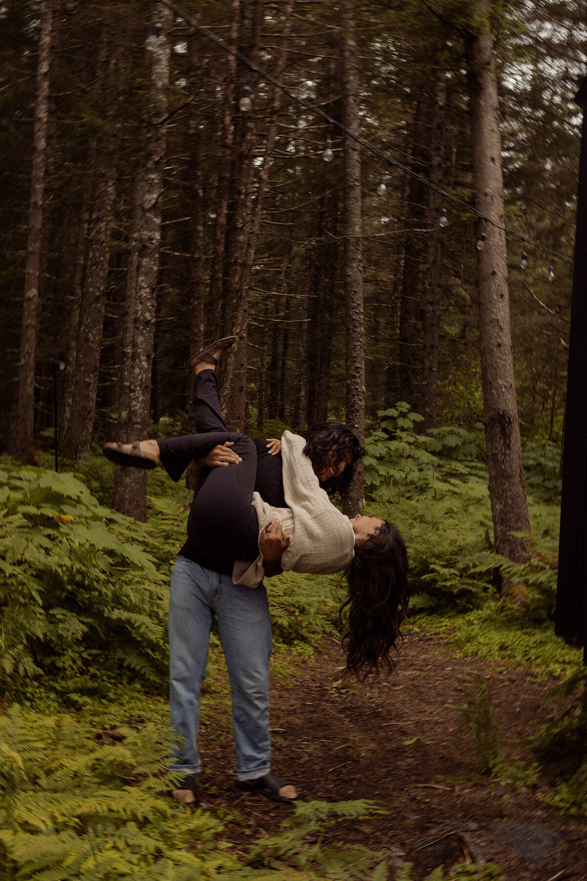 A person cradling their partner and dipping them in a forest 