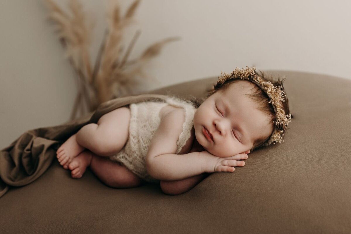 Peacefully sleeping newborn baby girl wearing a delicate floral crown and cream outfit during a studio photoshoot in Mullingar, Ireland.