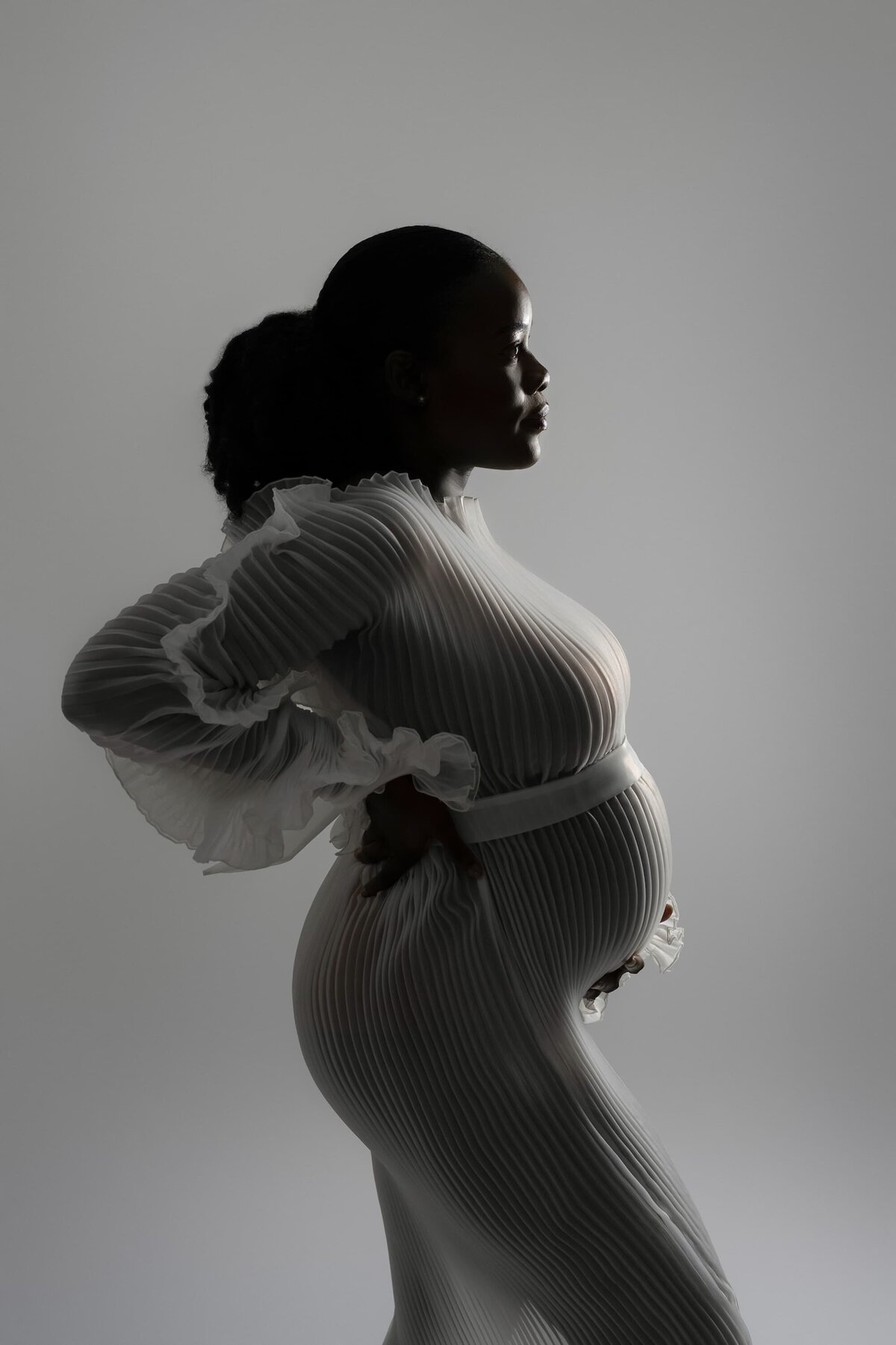pregnant woman wearing pleated maternity dress moody lighting