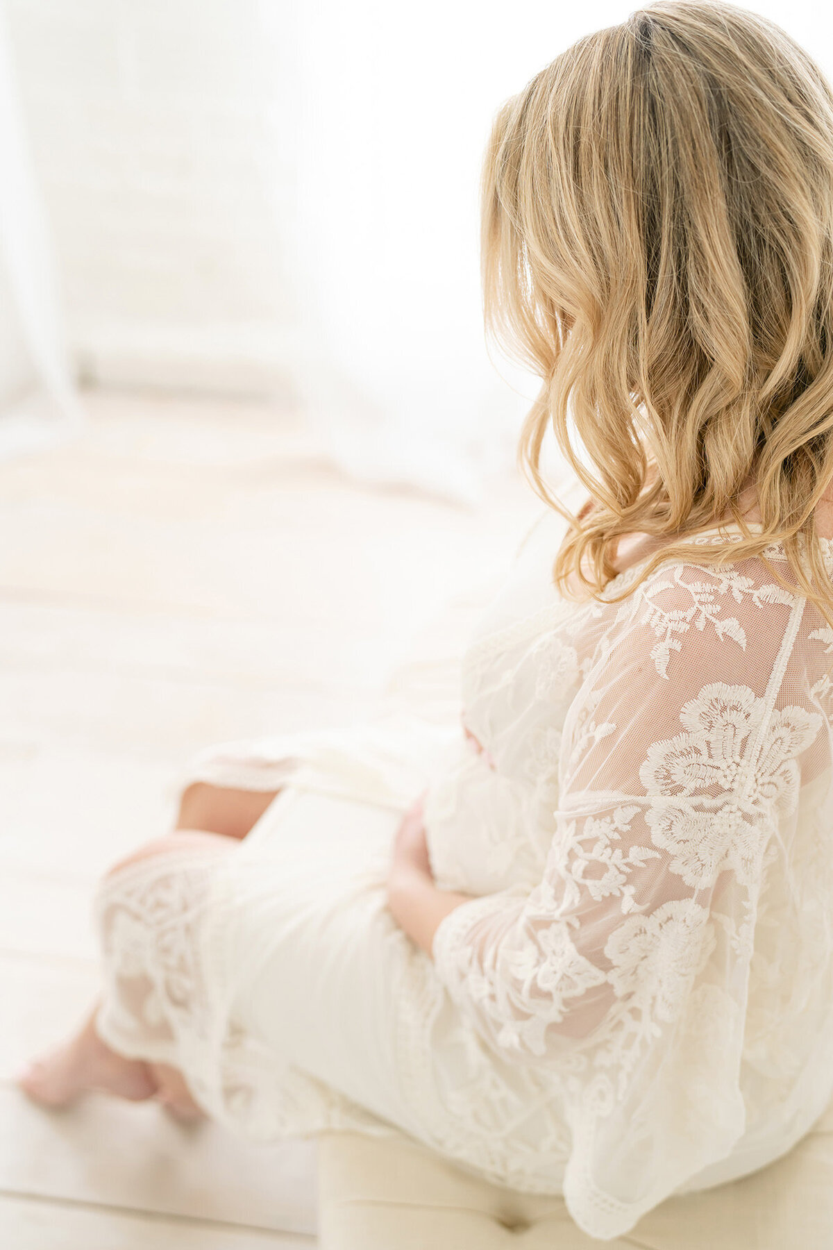 Over the shoulder of pregnant mom holding belly by Louisville maternity photographer