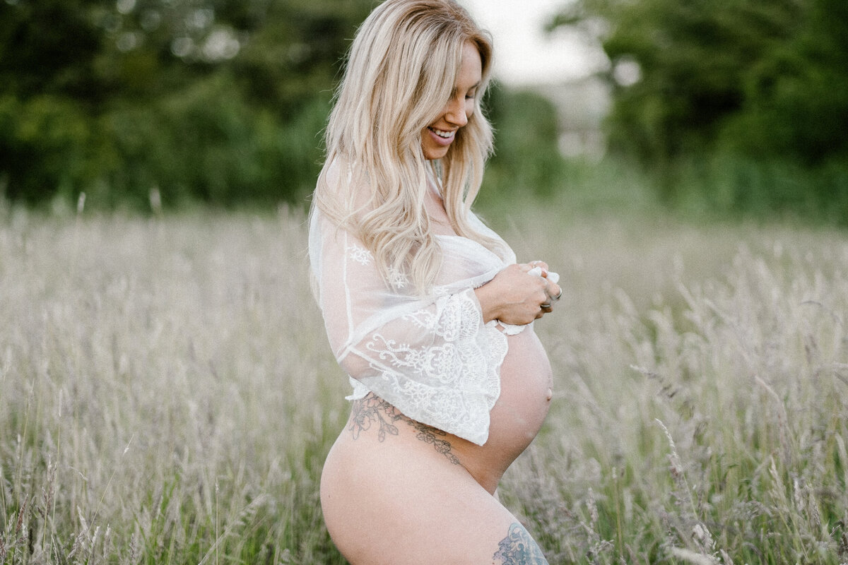 Mother stands in a field during her maternity photoshoot