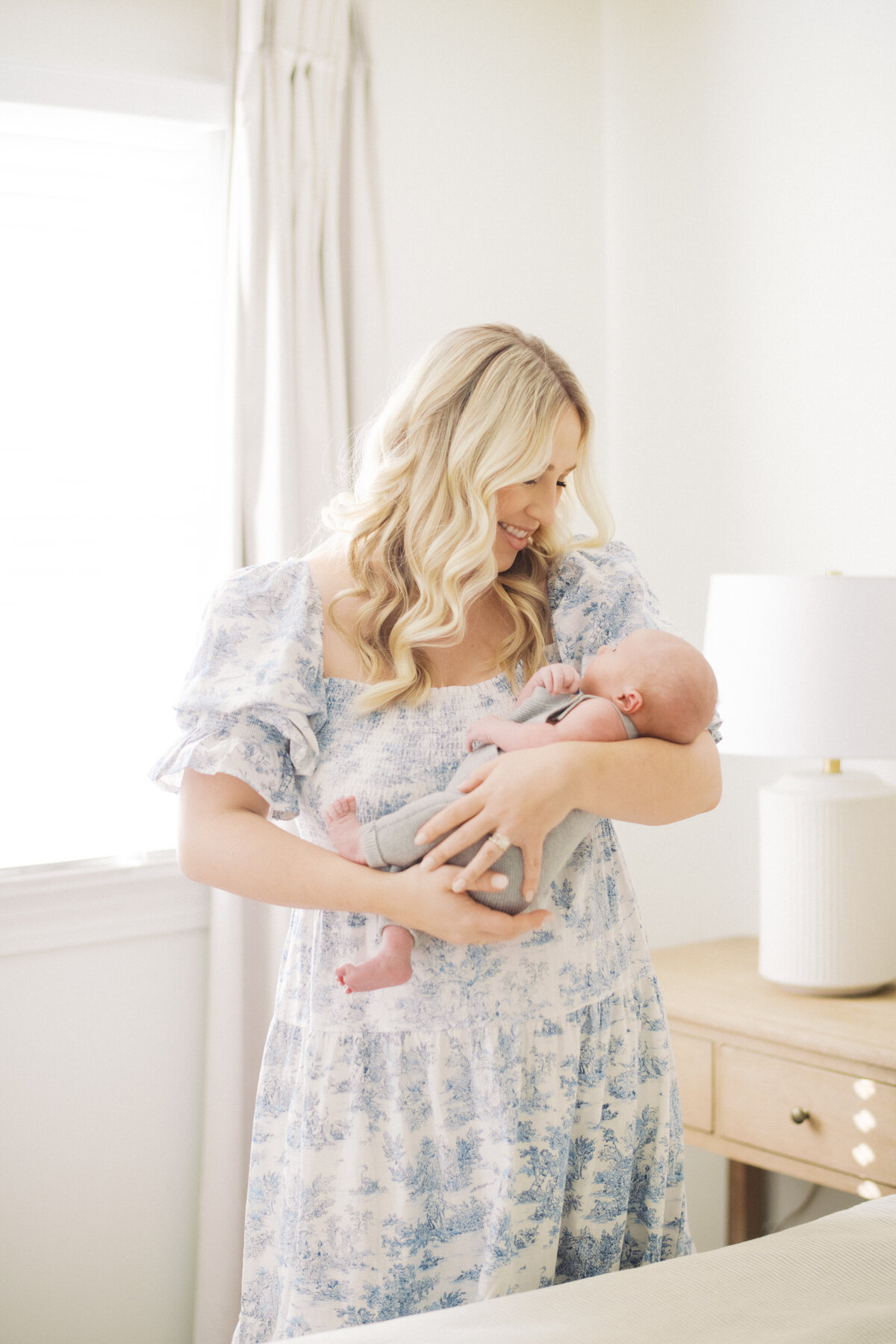 New mom holds her baby boy during a home newborn session in Raleigh. Image by Raleigh newborn photographer A.J. Dunlap Photography.