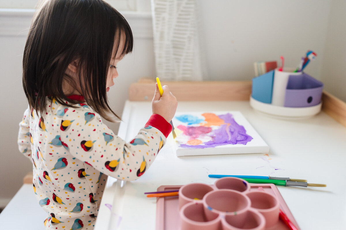 A little girl is drawing on canvas at her desk