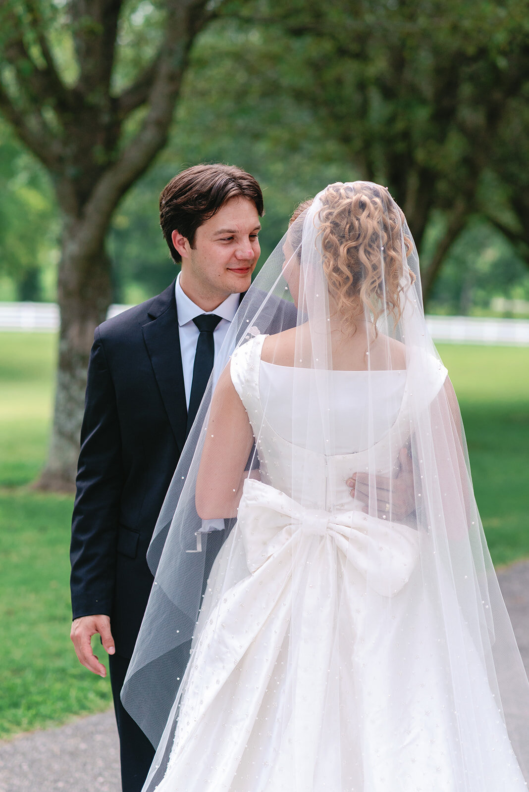 Bride in a white satin gown with large bow and long veil