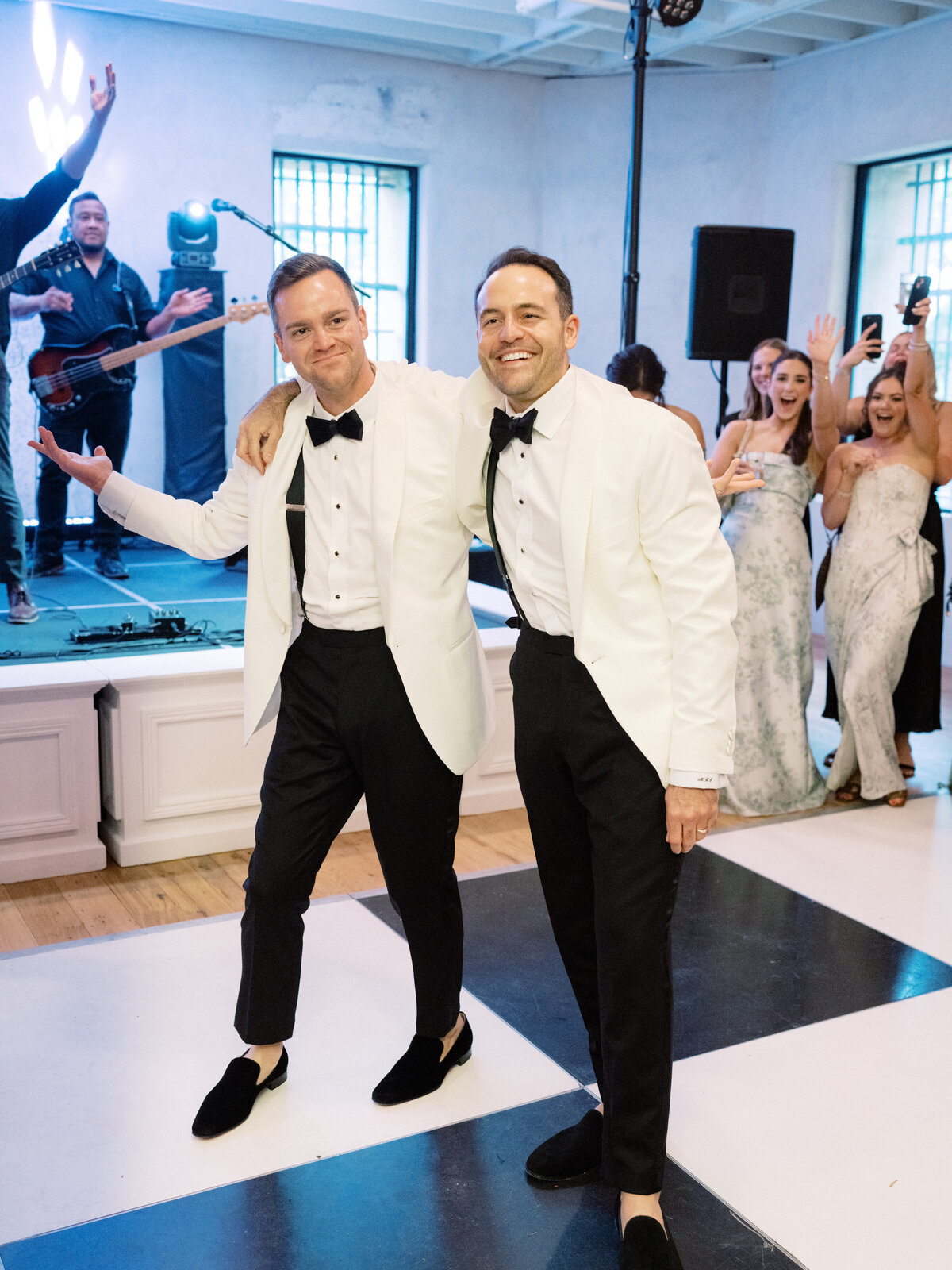 The couple strikes playful poses during their wedding reception, joyfully interacting with the lively atmosphere around them, embodying love's vibrant essence and companionship.