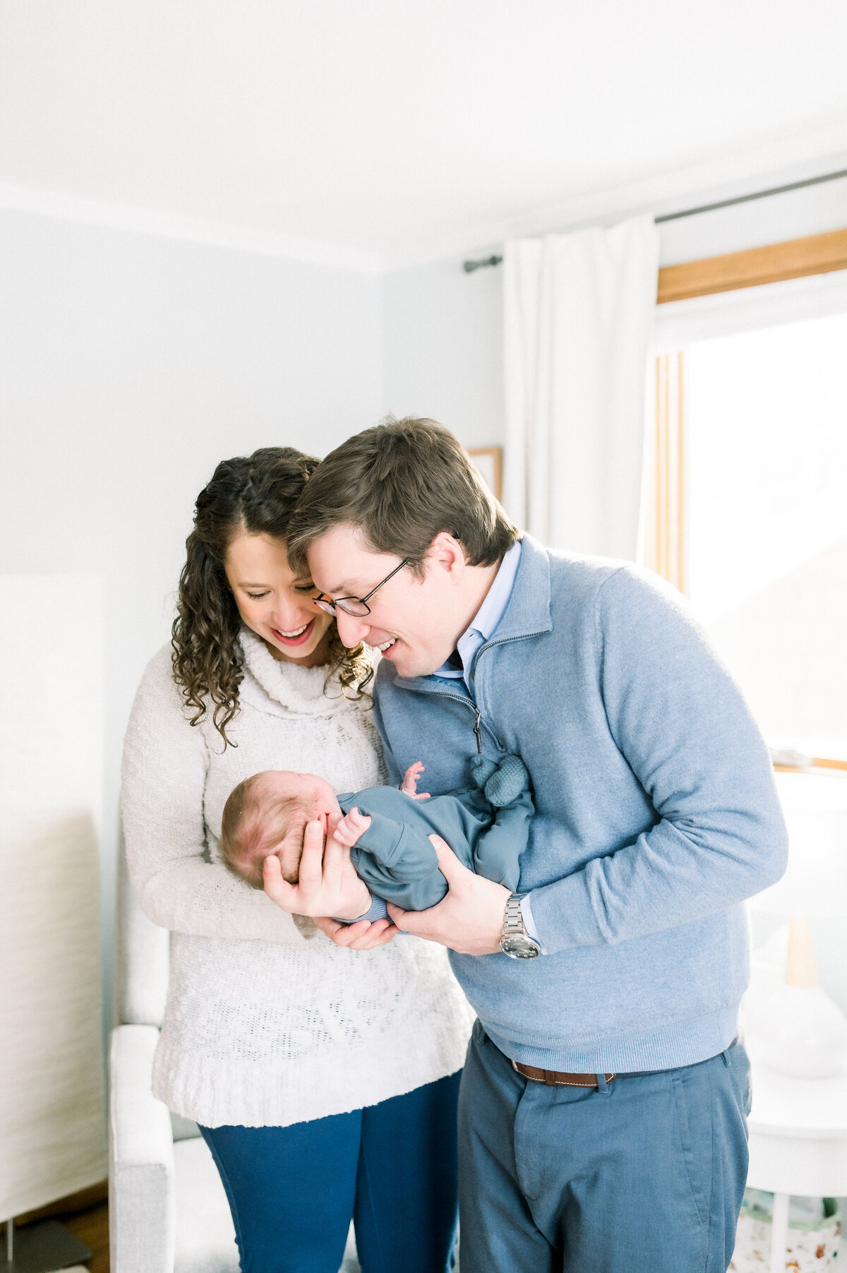 Mom and dad holding newborn baby in nursery