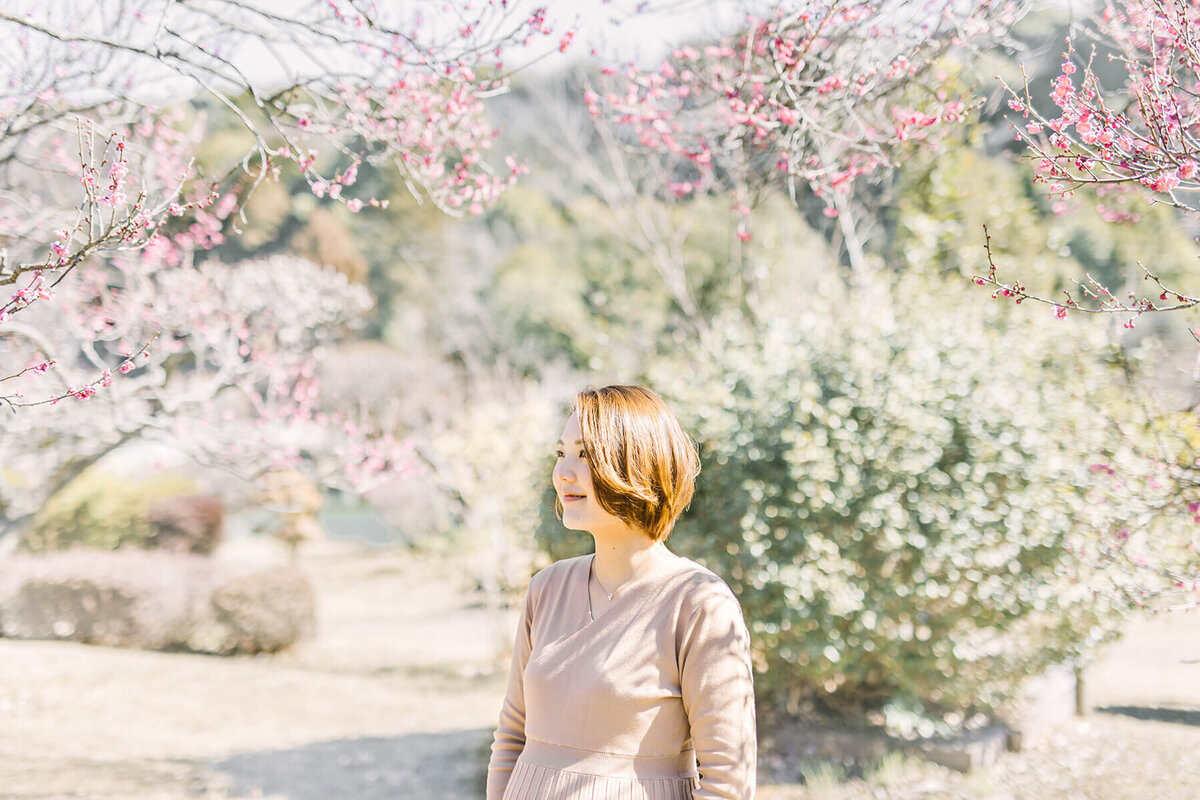 梅の花の下で、空を見上げている美しい妊婦さんのおしゃれで洗練されたマタニティフォト。町田市で撮影。