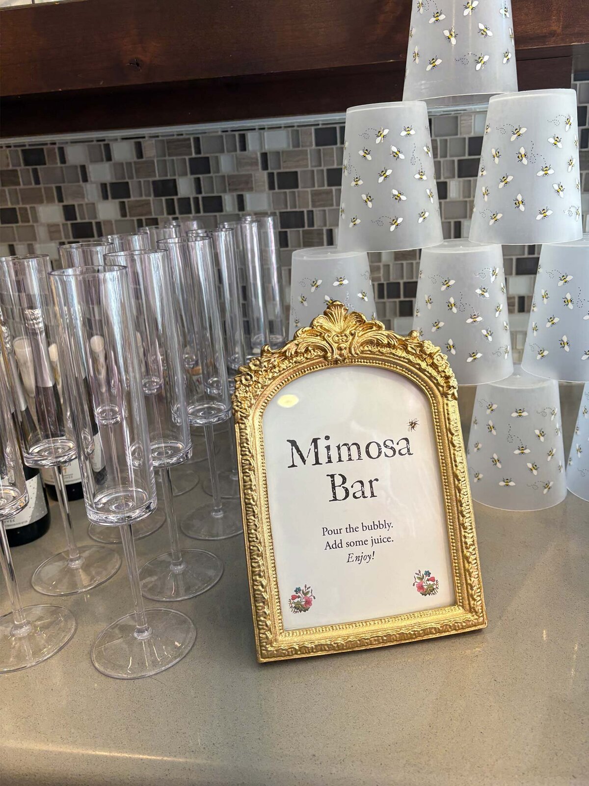 Mimosa bar custom event signage in gold antique frame with floral accents. Top to bottom: mimosa bar, pour the bubbly, add some juice, enjoy.