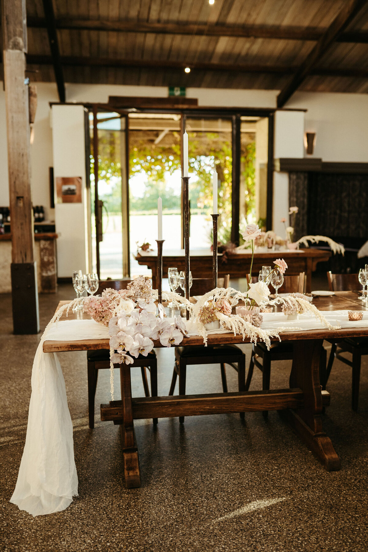 Modern and artfully arranged florals on long shared tables at Stones of the Yarra Valley