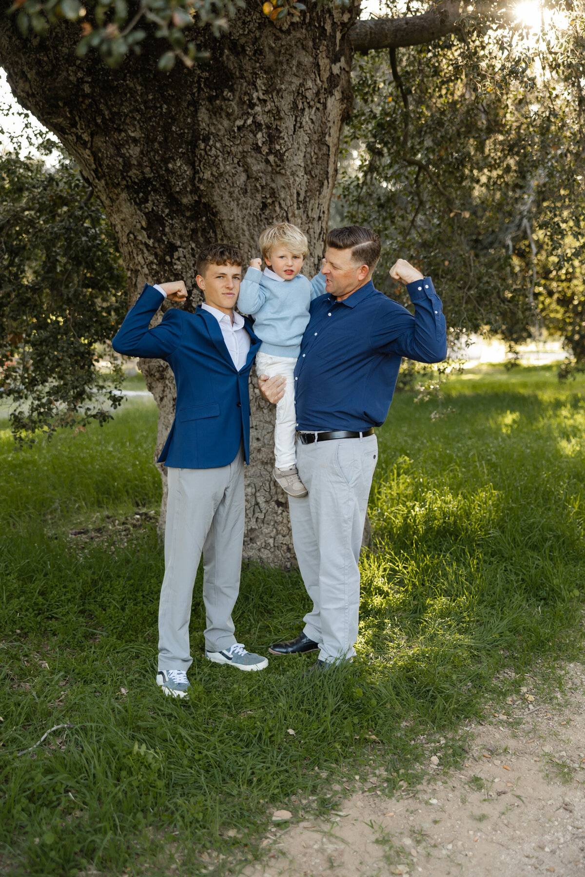 Two brothers with parents standing close together in matching blue blazers outdoors. Photographed by Yucaipa family photographer Kaitlyn Dawn Photography.