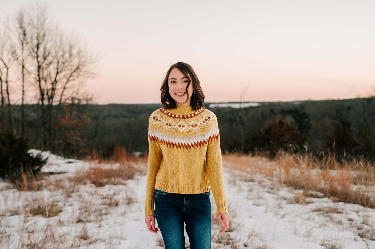 senior photo of girl walking in snow laughing walking on hiking trail in Branson
