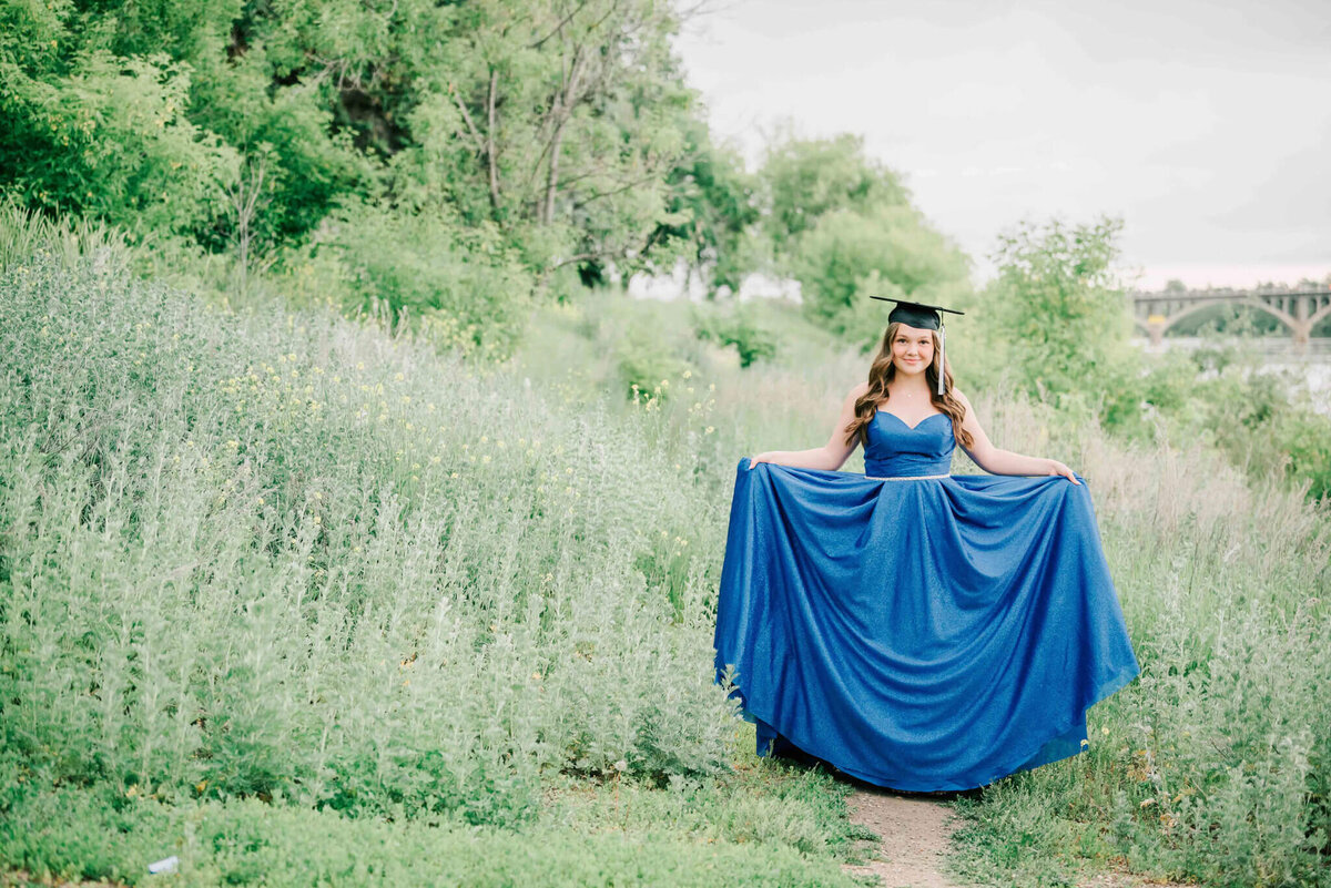 Holding dress out to the side and walking down a path. 