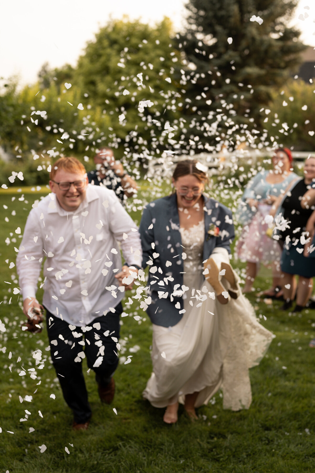 Bride and groom running through confetti taken by wedding photographers in Idaho.
