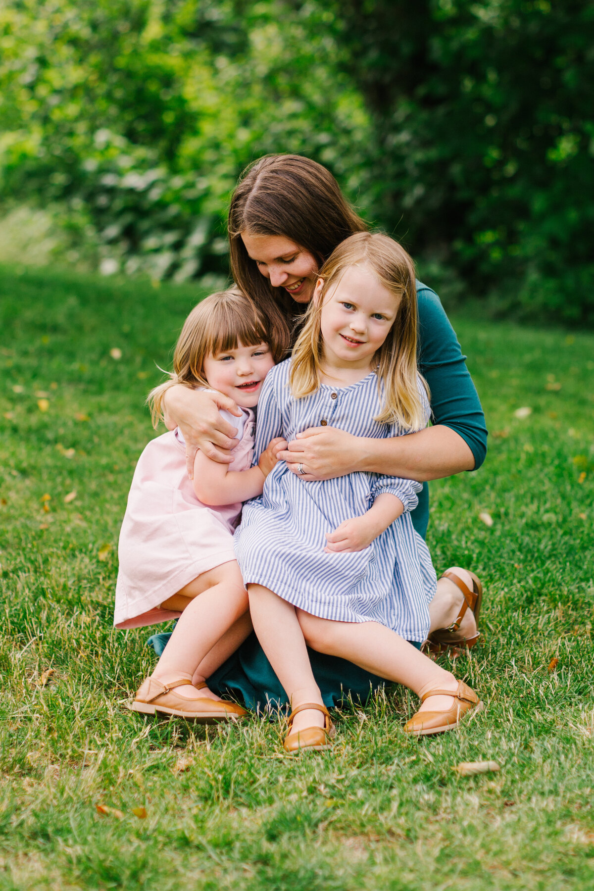 Mother kneeling in the grass with her two daughters