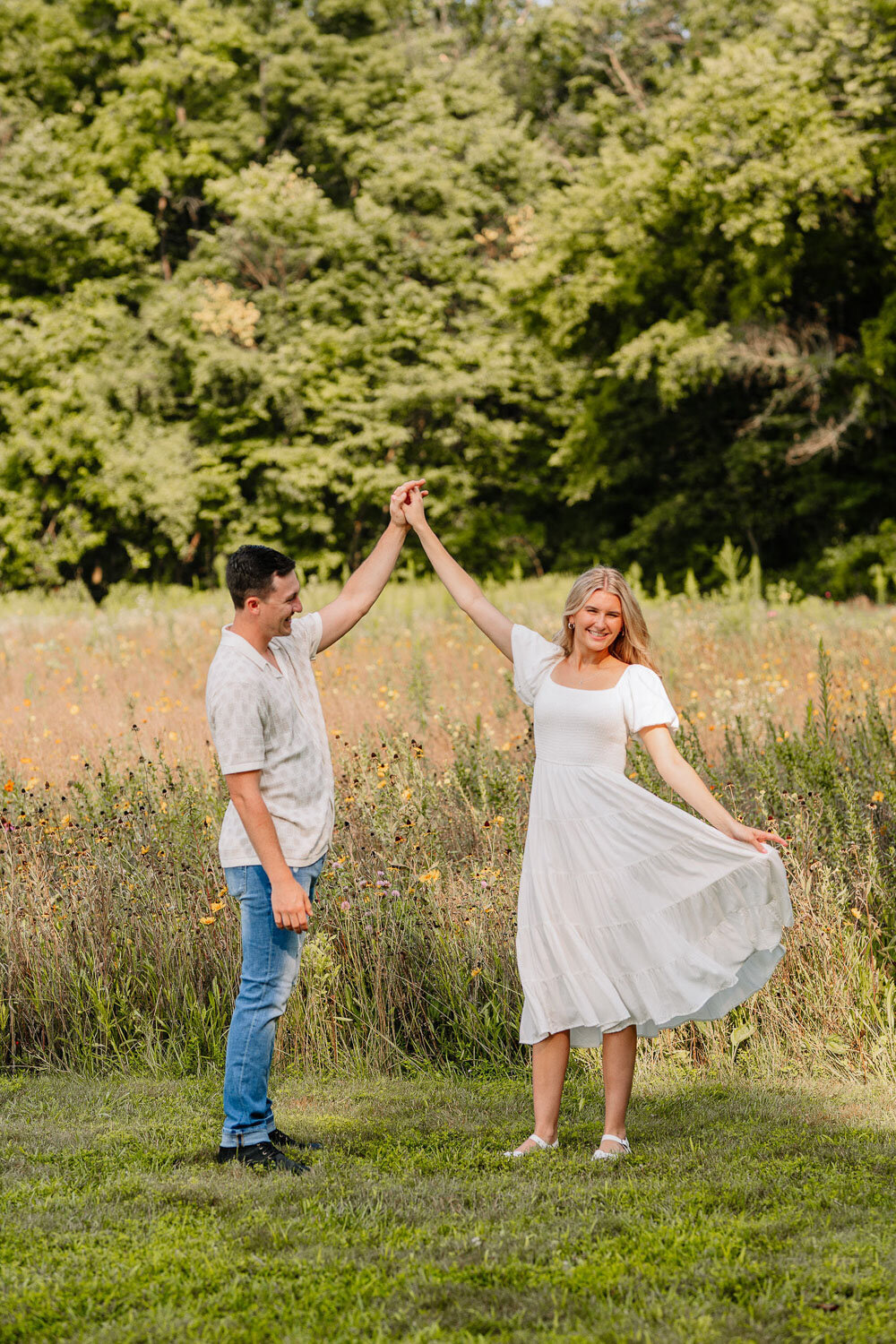 Couple dancing together in a field, with the woman twirling her dress