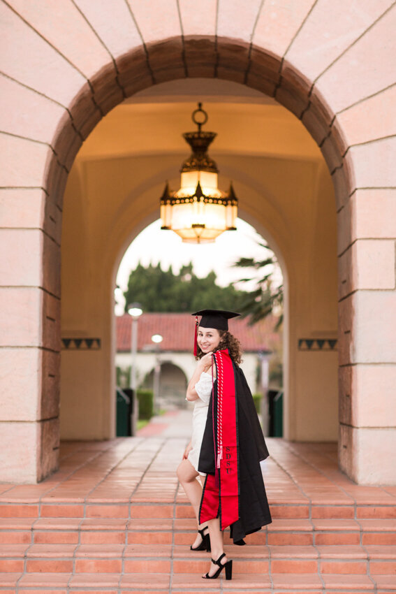 San Diego State senior with cap and gown on shoulder
