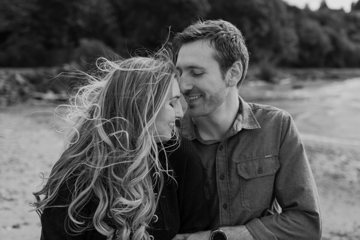 An engaged couple snuggles close at a beach.  Captured by Fort Worth wedding photographer, Megan Christine Studio
