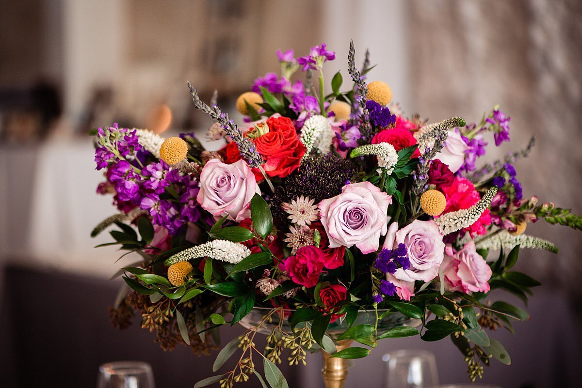 Delicate bridal bouquet made up of blush tea roses, purple and red flowers accents of small yellow  mums, purple wax flower and greenery.