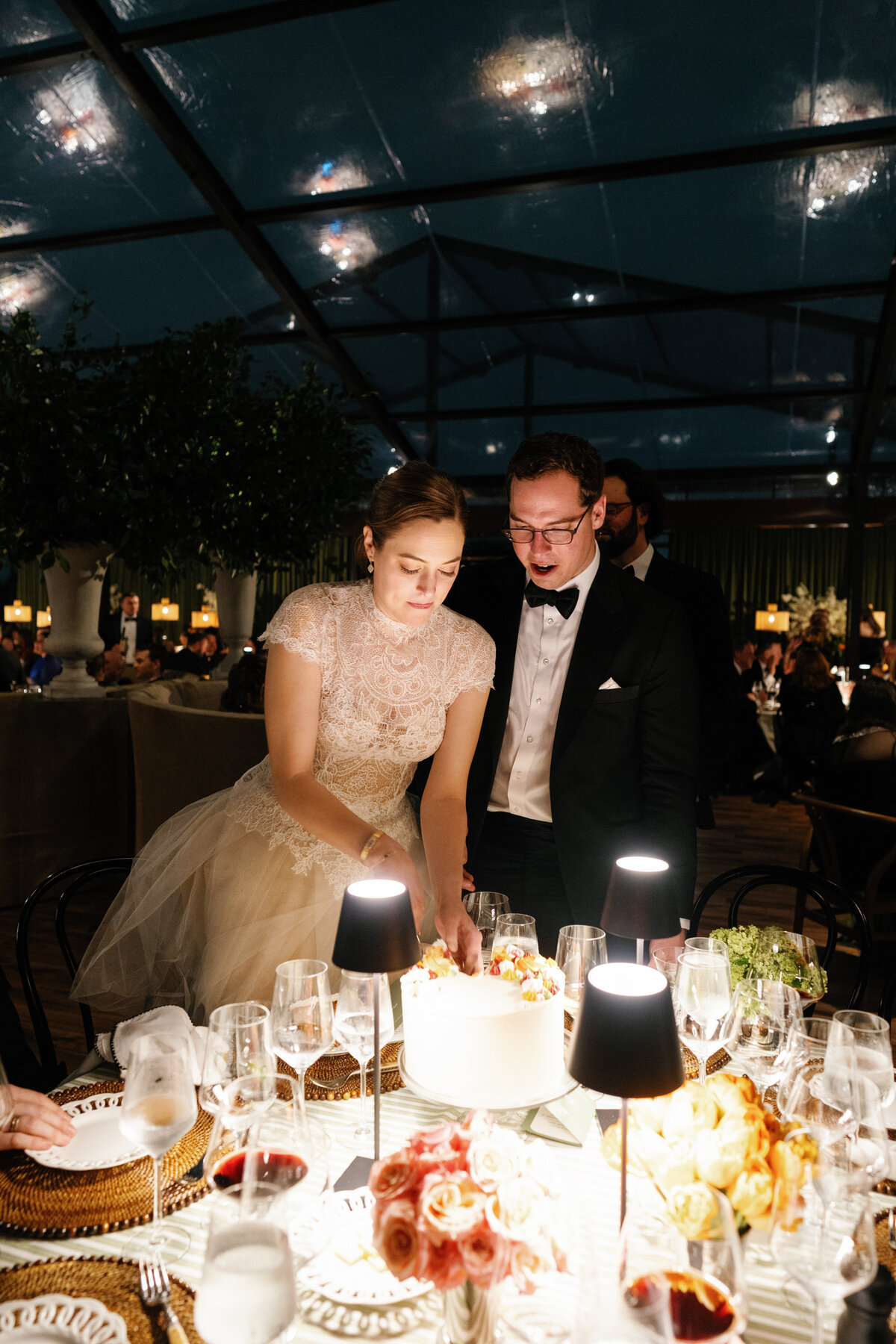 Bride and groom cutting a wedding cake at a guest table