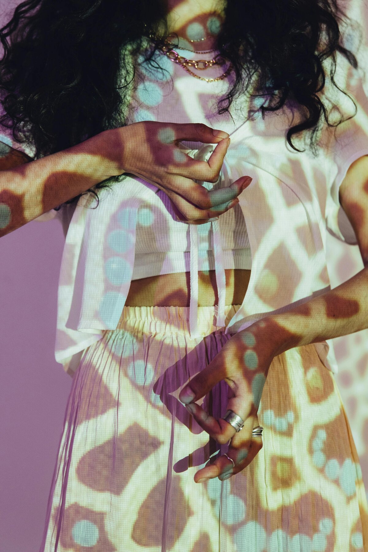 Close-up of a person with colorful, animal-print patterned light projected onto their body and clothing.