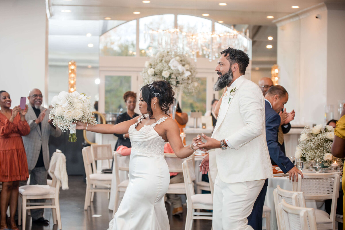 The newlyweds smile as they share a joyful dance, surrounded by friends and family.