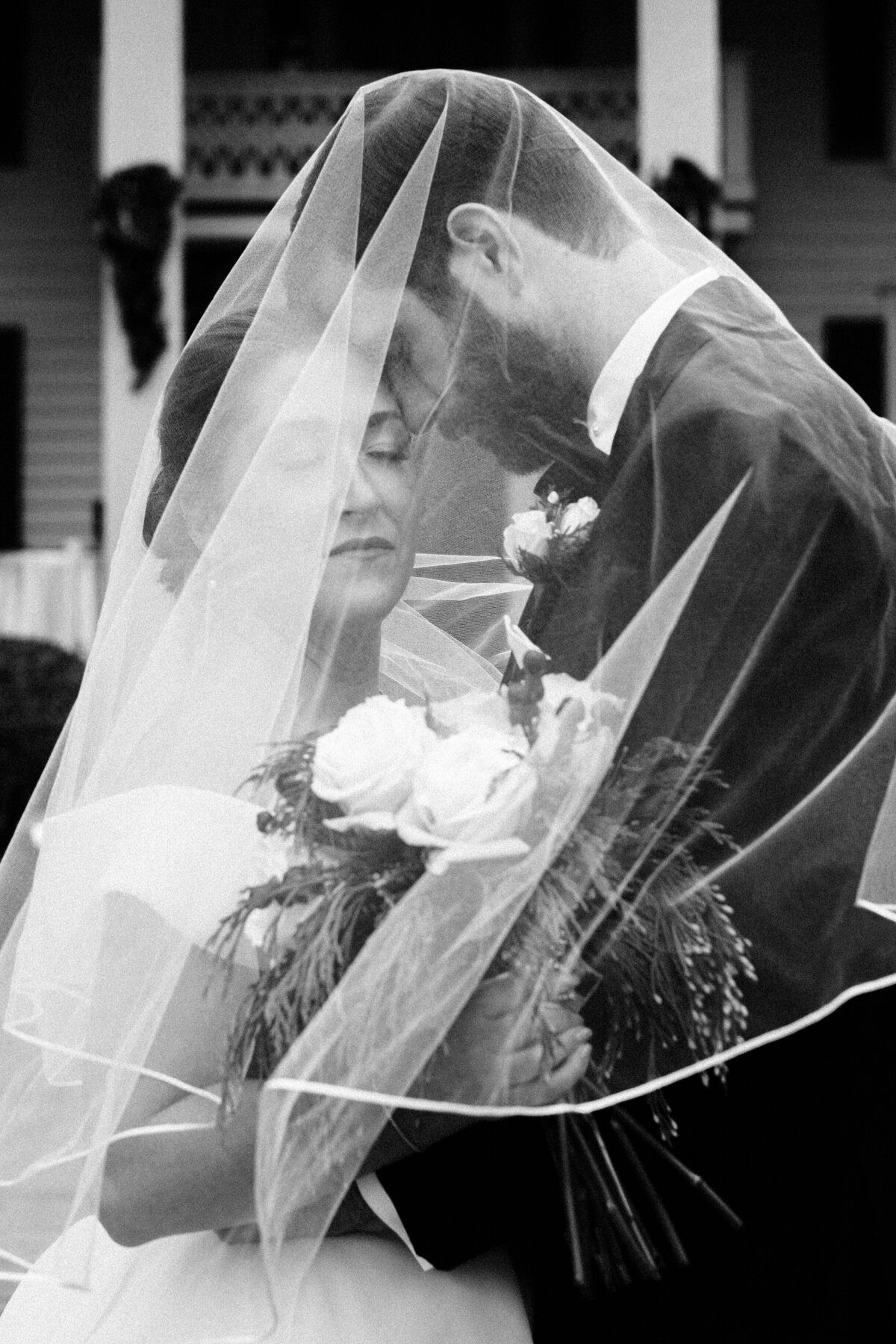 Bride and groom hugging under wedding veil