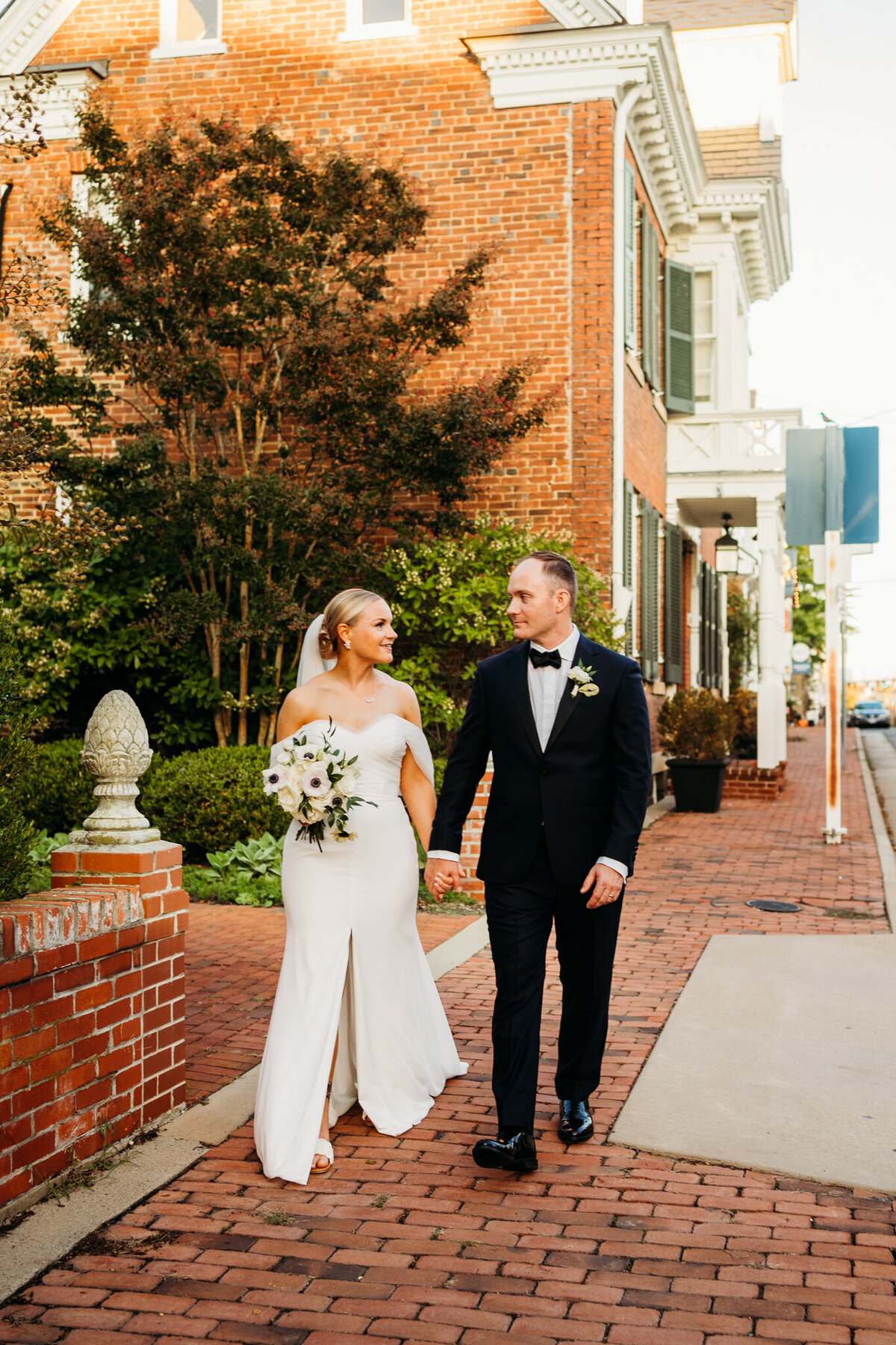  Stylish couple walking brick path outside historic downtown building