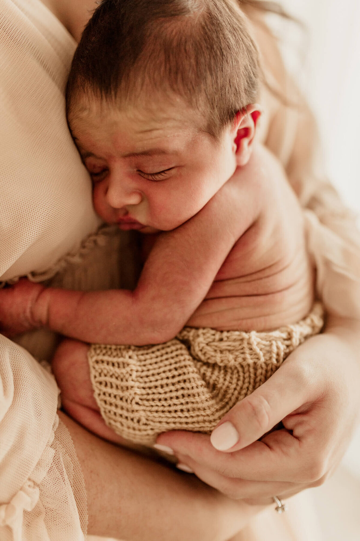 Baby boy hugs his mother while sleeping.