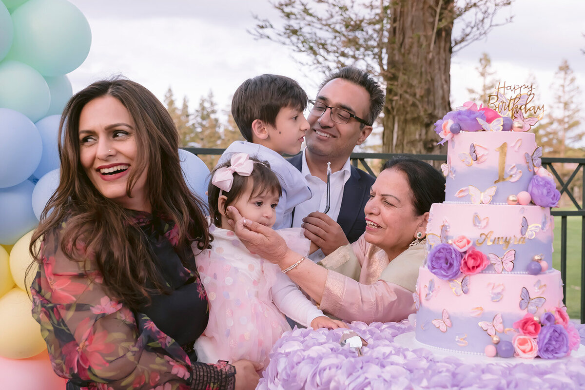 family-smiling-hugging-baby-birthday-cake-cutting