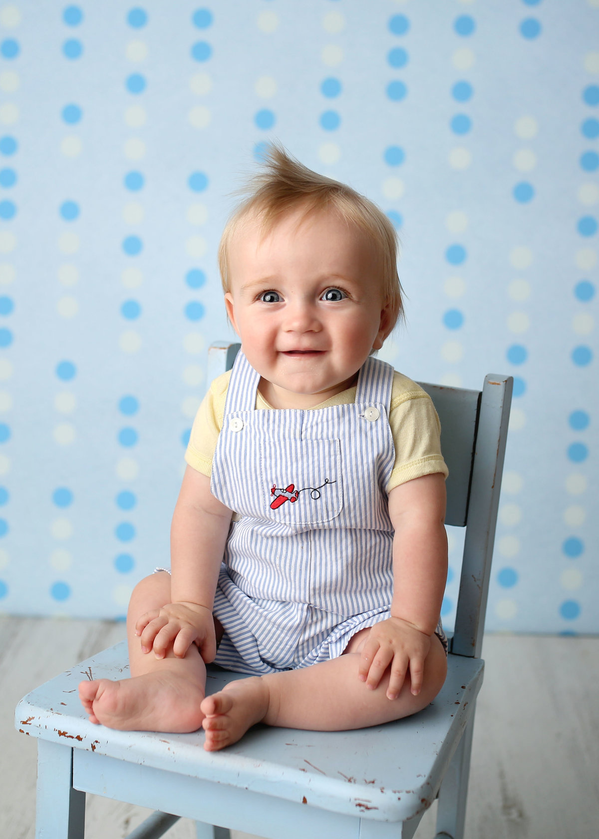 baby boy in striped blue overalls in antique chair