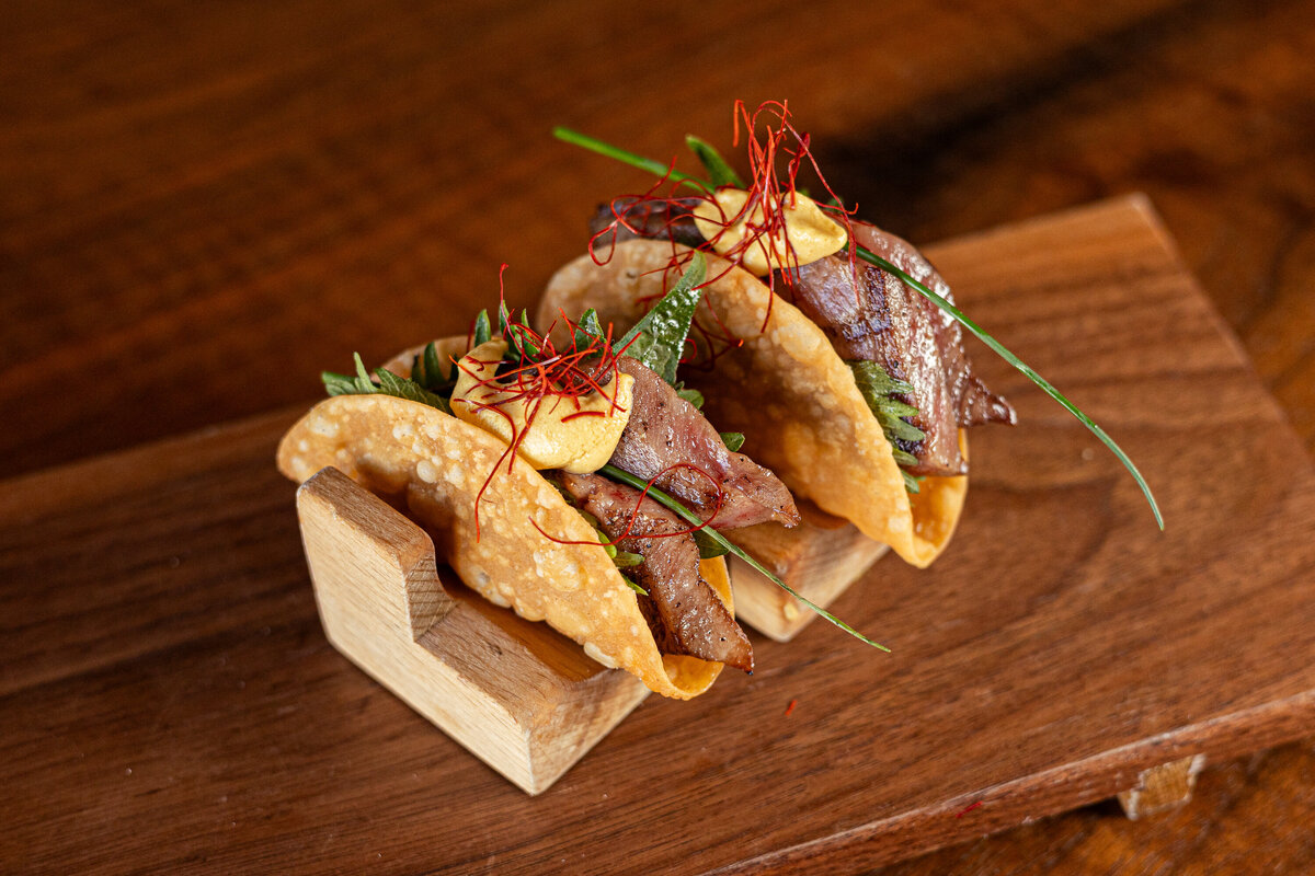 A pair of Wagyu Tacos sits on a wooden plate at Sushi Row in Colorado Springs.