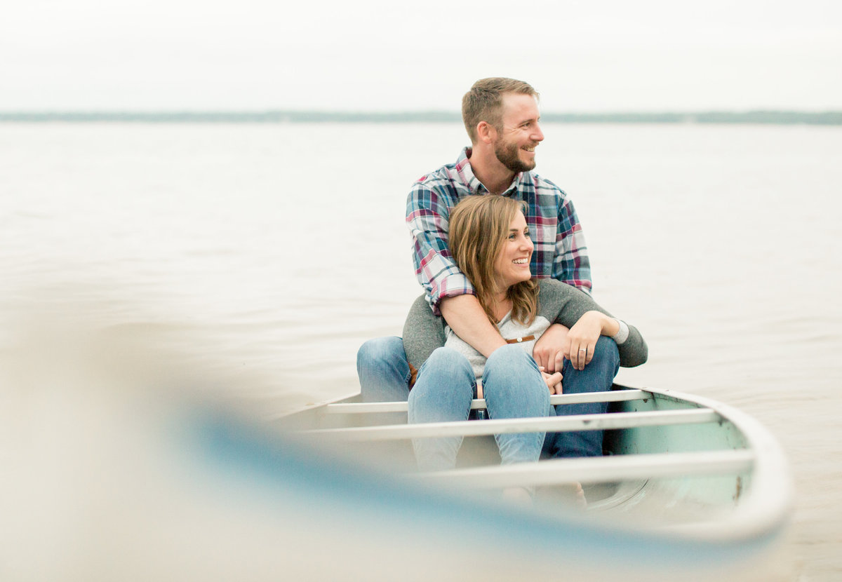 engaged couple sits in canoe on northwoods lake minnesota