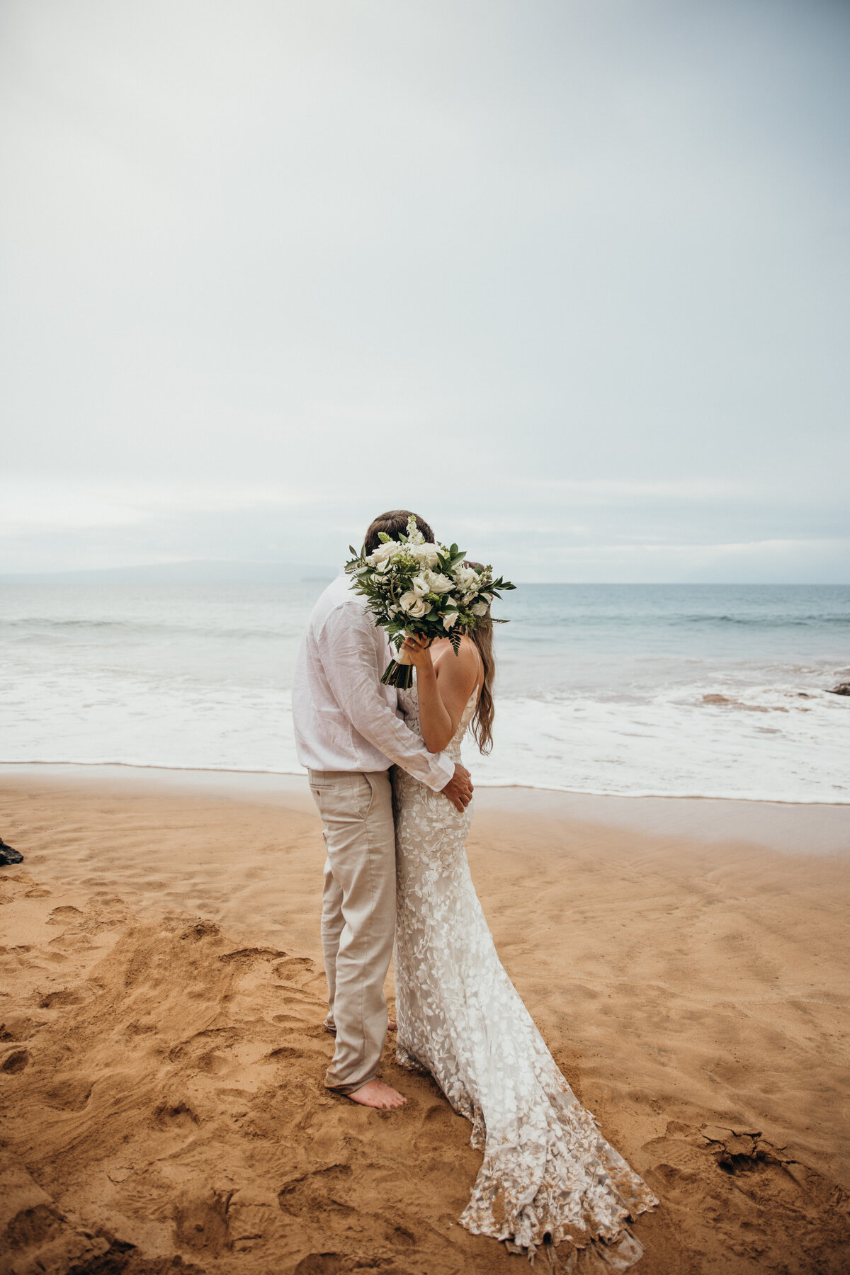 Maui Wedding Photographer captures bride and groom holding up bouquet during Maui beach wedding portraits