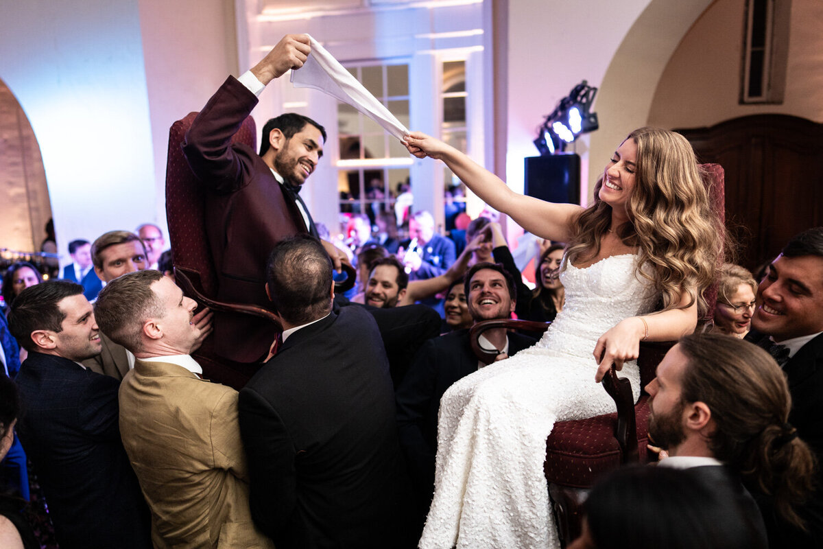 Bride and groom lifted on chairs at reception