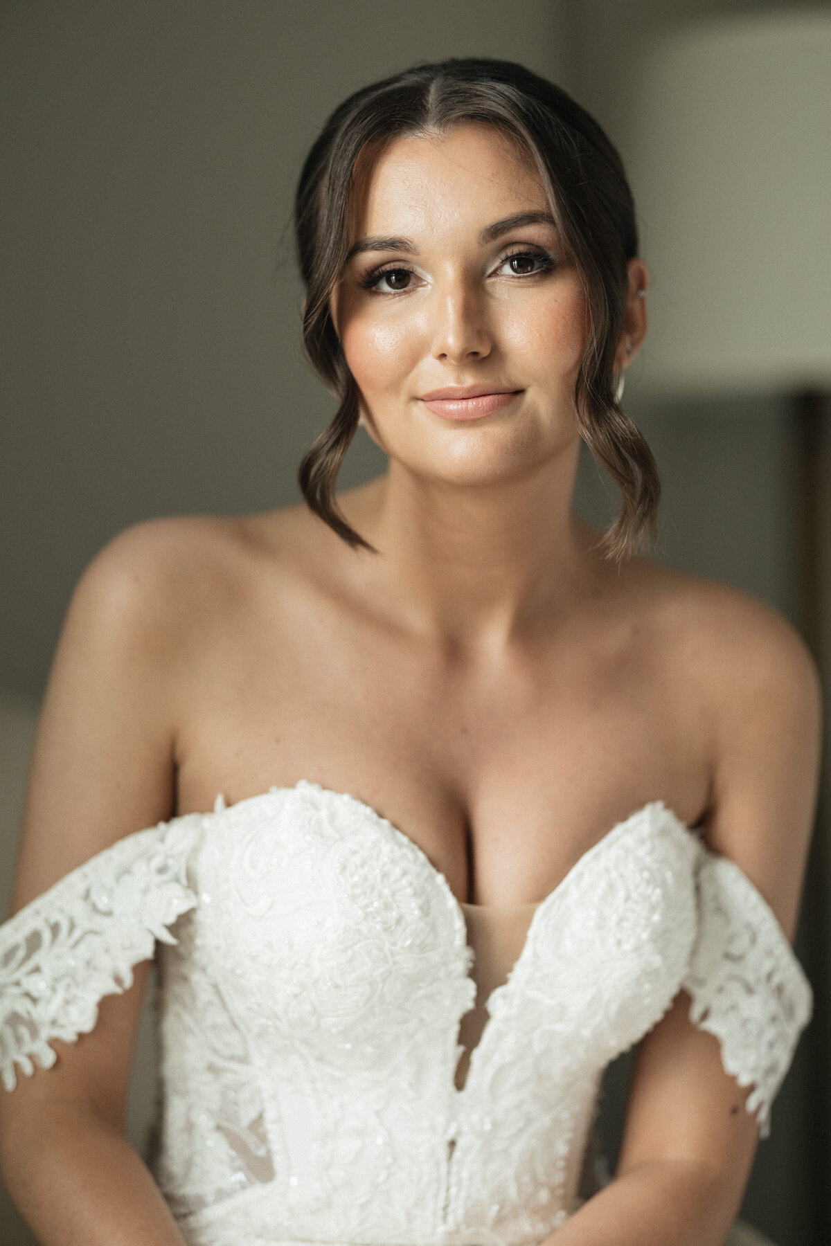 Bride looking into the camera as a soft light hits her from the window.